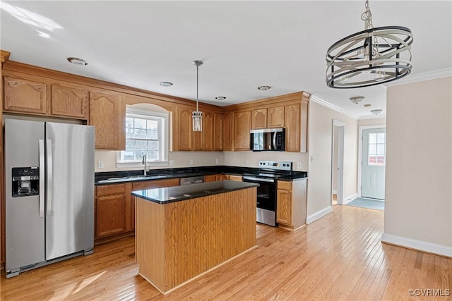 kitchen with a center island, crown molding, stainless steel appliances, light wood-style flooring, and a sink