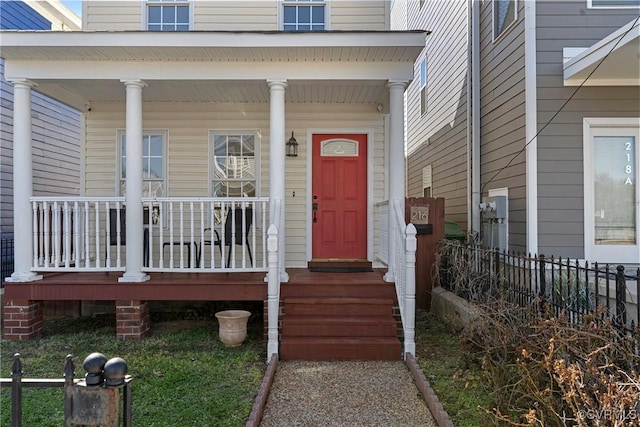 doorway to property featuring a porch and fence