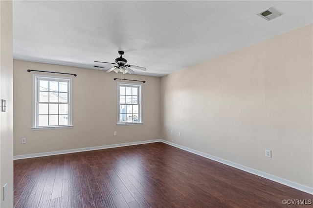 spare room featuring a ceiling fan, baseboards, visible vents, and dark wood-style flooring