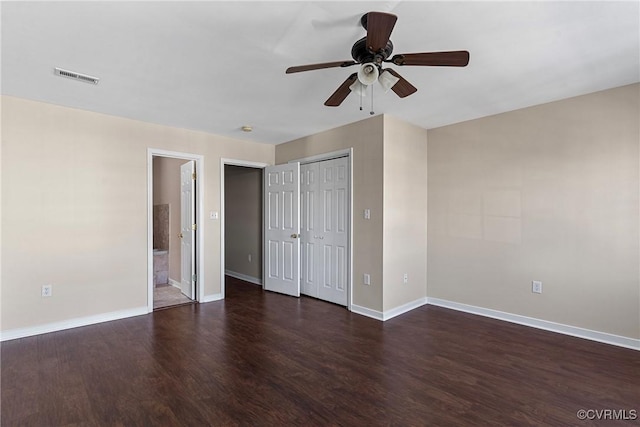 unfurnished bedroom featuring visible vents, a ceiling fan, ensuite bath, wood finished floors, and baseboards