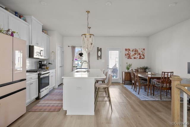 kitchen with light wood-style flooring, a sink, light countertops, appliances with stainless steel finishes, and backsplash