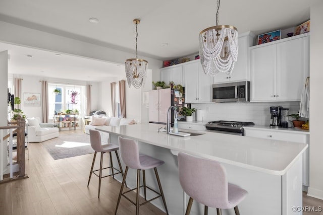 kitchen featuring a breakfast bar area, stainless steel appliances, a sink, open floor plan, and backsplash