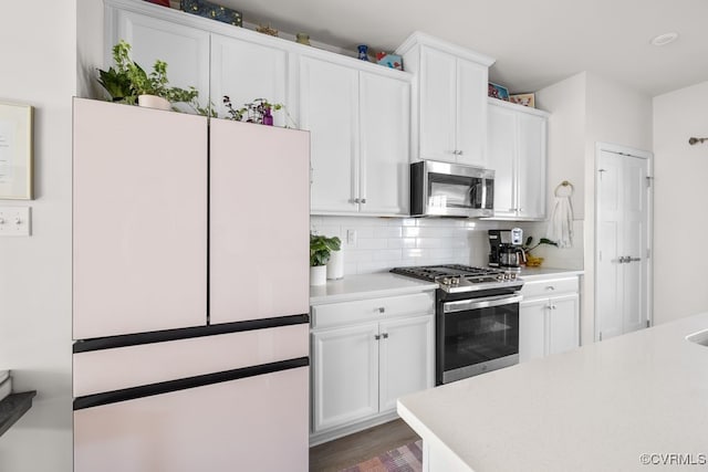 kitchen featuring white cabinets, appliances with stainless steel finishes, light countertops, and decorative backsplash