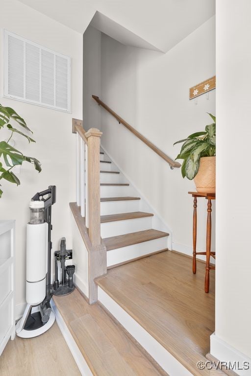 stairway featuring baseboards, visible vents, and wood finished floors