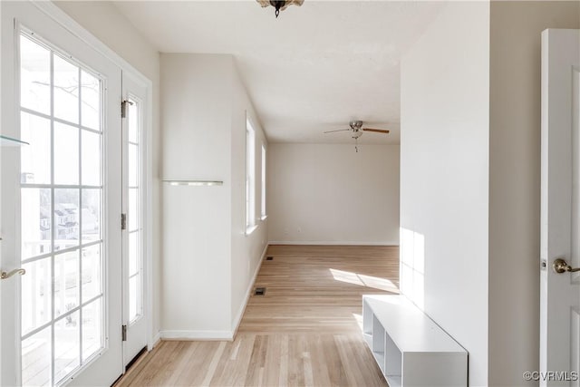 hall with light wood-style floors, visible vents, and baseboards