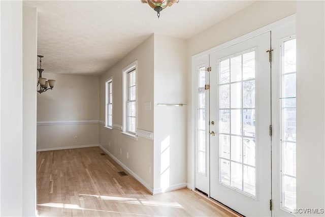 entryway with a healthy amount of sunlight, visible vents, baseboards, and wood finished floors