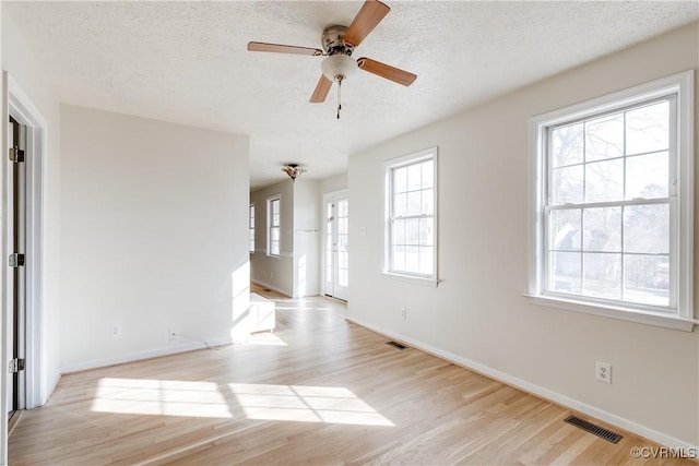 spare room featuring plenty of natural light, a textured ceiling, light wood-type flooring, and visible vents