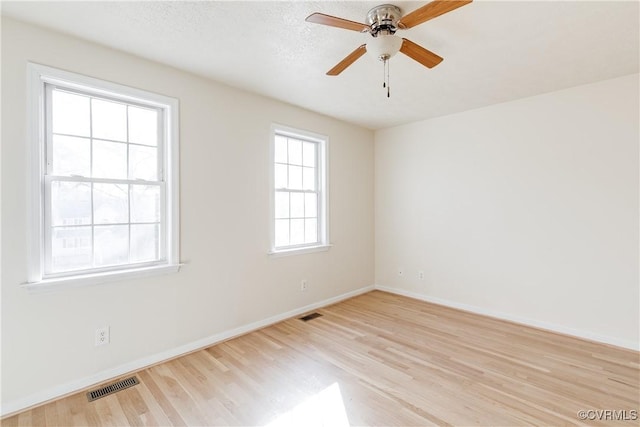 spare room featuring ceiling fan, light wood-type flooring, visible vents, and baseboards