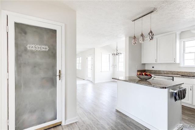 kitchen with dark stone counters, white cabinetry, a textured ceiling, and light wood finished floors