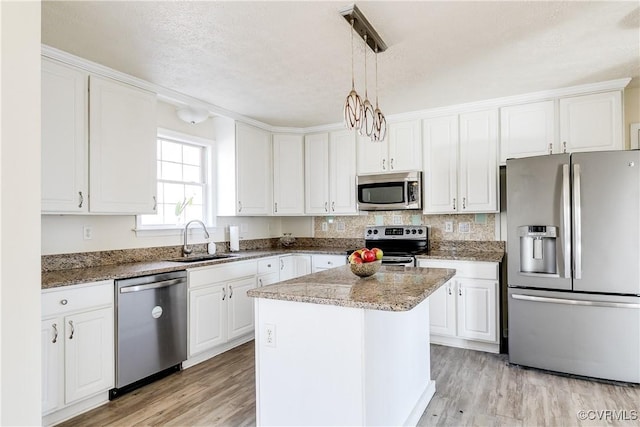 kitchen with stainless steel appliances, a sink, light wood-style flooring, and white cabinets