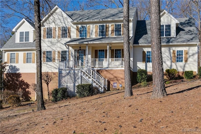 view of front of home with covered porch, roof with shingles, and stairs