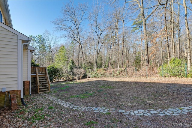 view of yard with stairway, a deck, and a wooded view