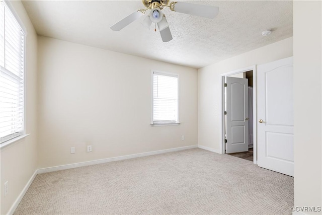 carpeted empty room with a ceiling fan, a textured ceiling, and baseboards