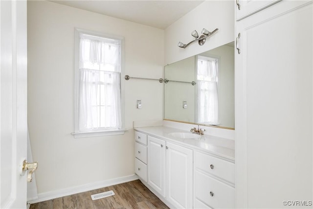 bathroom featuring baseboards, visible vents, wood finished floors, and vanity