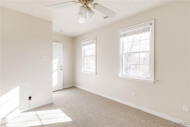 spare room with light colored carpet, ceiling fan, visible vents, and baseboards