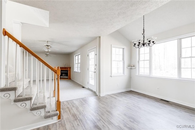 foyer with visible vents, stairway, wood finished floors, a textured ceiling, and a fireplace