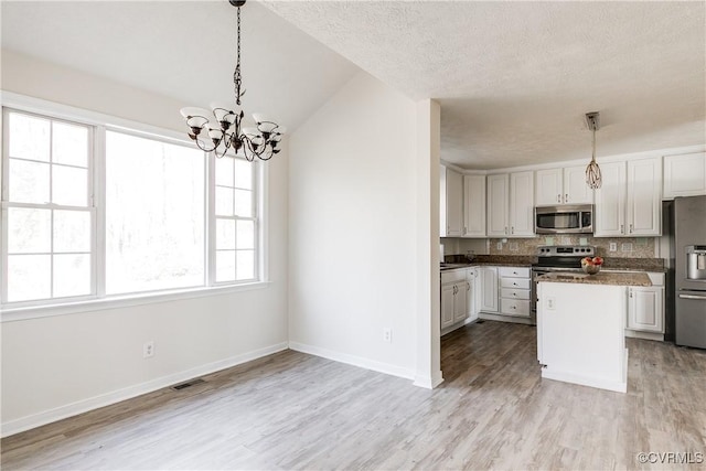 kitchen with light wood finished floors, baseboards, decorative light fixtures, a center island, and stainless steel appliances