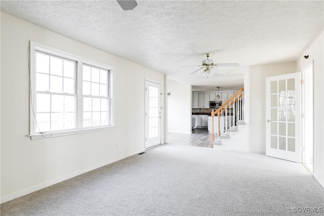 spare room featuring a ceiling fan, carpet flooring, stairway, and a textured ceiling