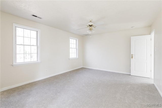 empty room with a ceiling fan, carpet, visible vents, and baseboards