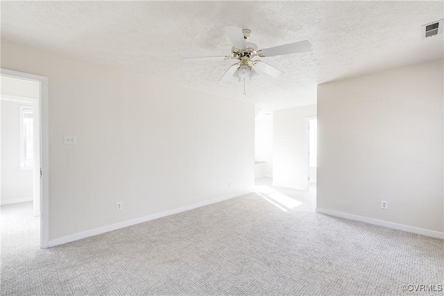 unfurnished room featuring carpet, visible vents, a ceiling fan, a textured ceiling, and baseboards