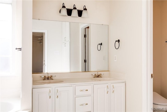 full bath featuring double vanity, a sink, and toilet