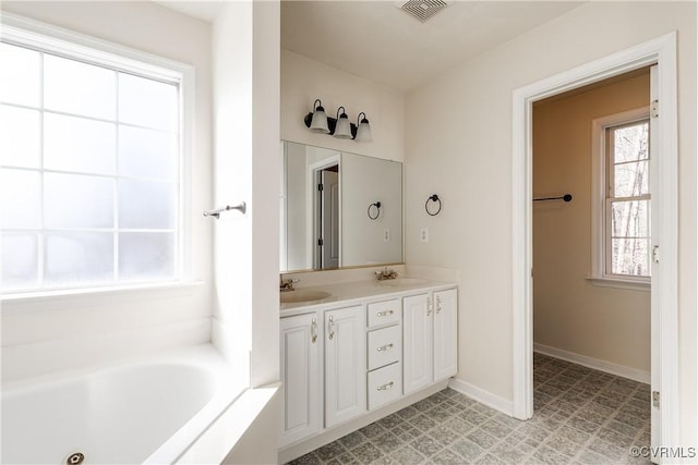 bathroom featuring a bath, double vanity, visible vents, and a sink