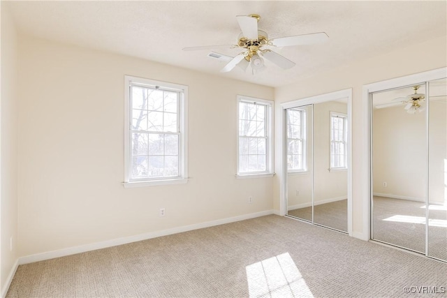 unfurnished bedroom featuring carpet flooring, two closets, and baseboards