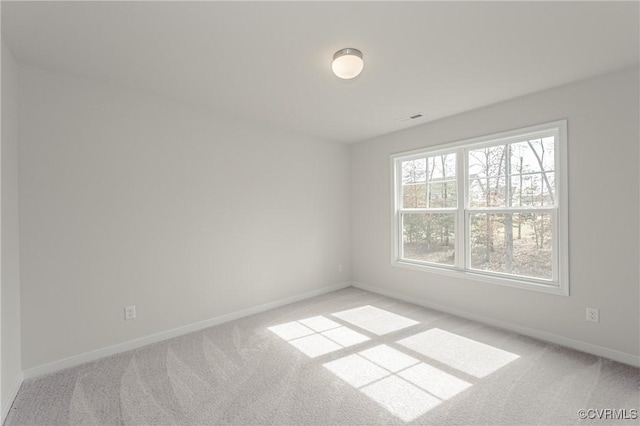 empty room featuring baseboards, light colored carpet, and visible vents