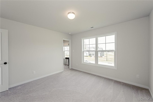 spare room featuring baseboards, light colored carpet, and visible vents