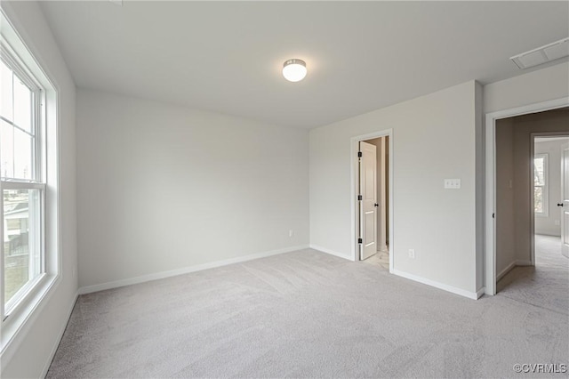 spare room featuring light colored carpet, baseboards, and visible vents