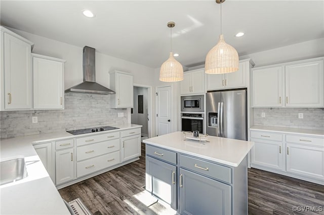 kitchen with wall chimney range hood, dark wood-style flooring, stainless steel appliances, white cabinetry, and backsplash
