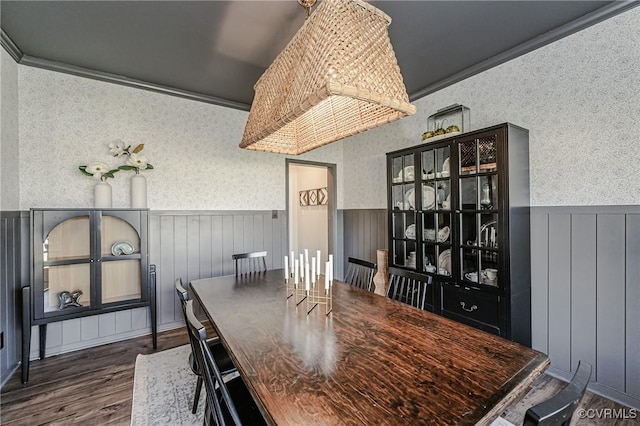 dining space with ornamental molding, wainscoting, wallpapered walls, and wood finished floors