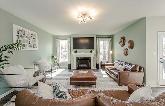 living room with baseboards, a glass covered fireplace, and plenty of natural light