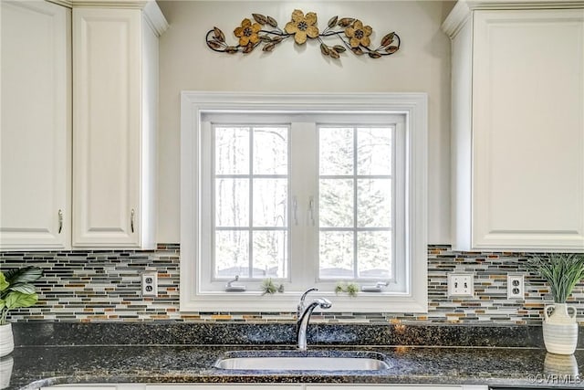 kitchen featuring white cabinets, a healthy amount of sunlight, tasteful backsplash, and a sink