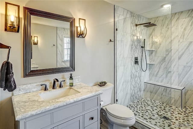 bathroom with tiled shower, toilet, and vanity