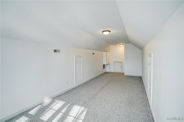 additional living space featuring lofted ceiling, light colored carpet, visible vents, and baseboards