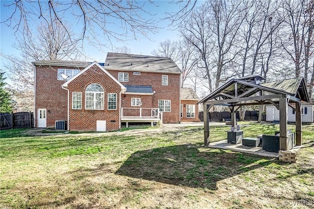 back of property featuring brick siding, fence, central AC, a gazebo, and a lawn