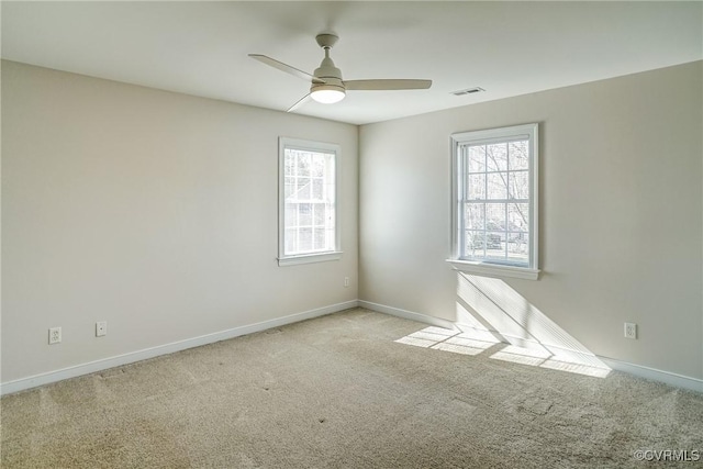 carpeted spare room featuring a ceiling fan, visible vents, and baseboards