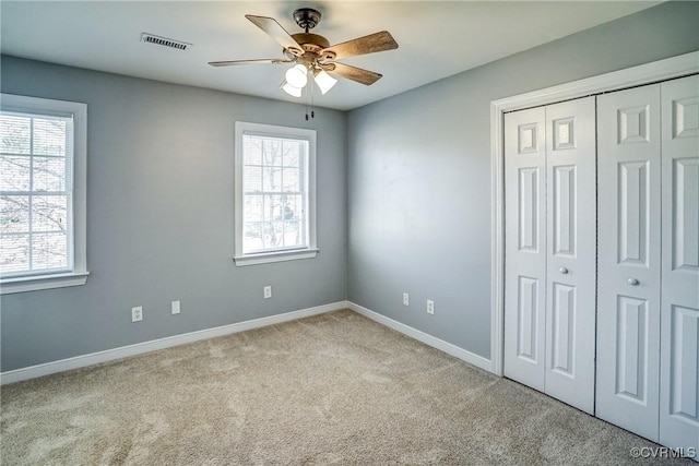 unfurnished bedroom featuring visible vents, baseboards, carpet, a closet, and a ceiling fan