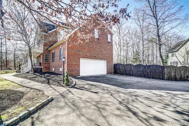 view of side of home with aphalt driveway, a gate, fence, and brick siding