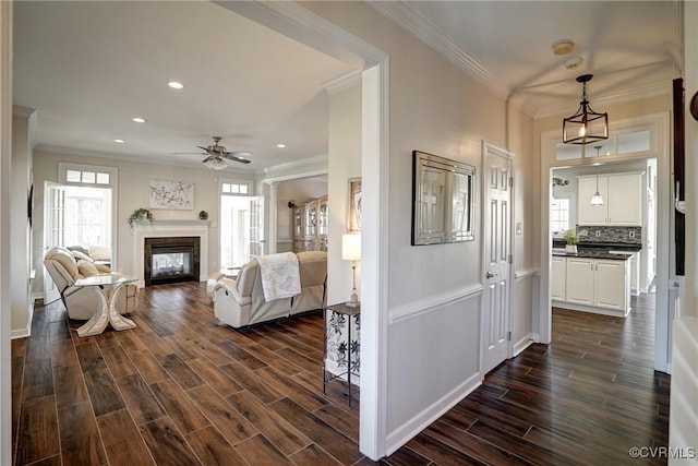 interior space with wood finish floors, recessed lighting, a glass covered fireplace, and crown molding