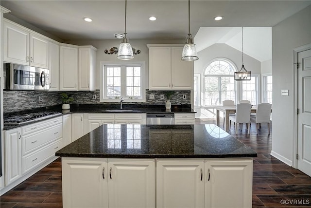 kitchen with wood finish floors, backsplash, appliances with stainless steel finishes, and a sink