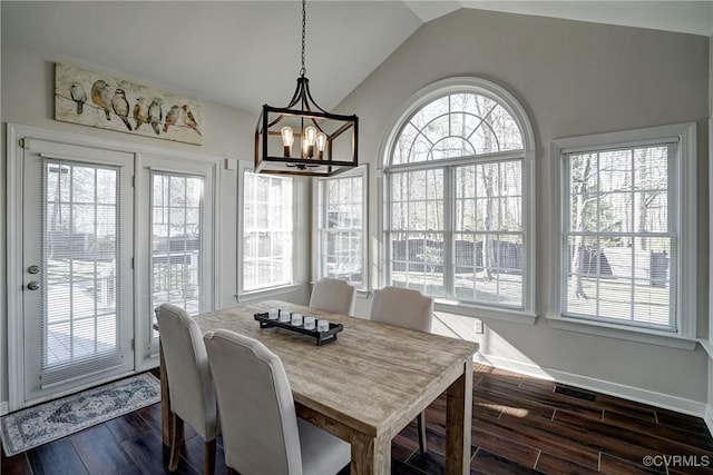 dining space featuring lofted ceiling, dark wood-style floors, baseboards, and a chandelier