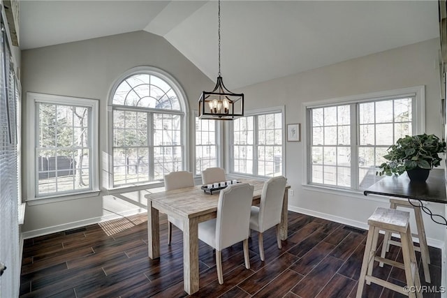 dining area featuring wood finish floors, baseboards, lofted ceiling, and an inviting chandelier