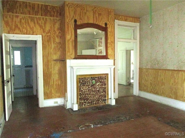 unfurnished living room with a wainscoted wall and wood walls