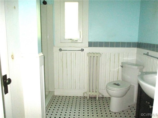 bathroom with toilet, a wainscoted wall, and radiator