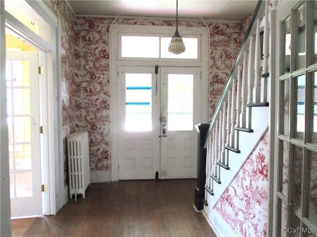 foyer featuring radiator, wallpapered walls, stairs, and french doors