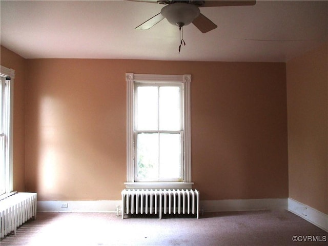 carpeted empty room featuring radiator heating unit, plenty of natural light, and baseboards