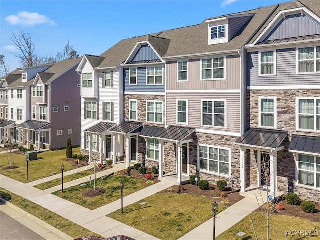 townhome / multi-family property featuring a residential view, metal roof, roof with shingles, a standing seam roof, and a front lawn