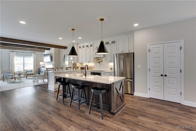 kitchen with dark wood-style flooring, freestanding refrigerator, tasteful backsplash, a kitchen bar, and glass insert cabinets